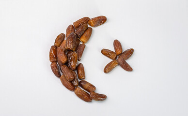 The fruits of dates laid out in the shape of a crescent and a star. The concept of nostalgia, memories. Isolated on a white background.