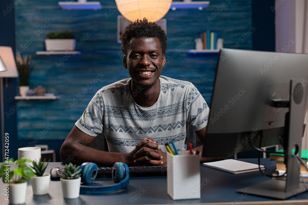 Poster portrait of smiling african american man using computer while working remote from home at marketing 