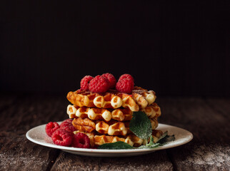 yummy belgian waffles with raspberries and mint leaves on wooden table 