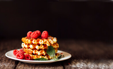 yummy belgian waffles with raspberries and mint leaves on wooden table 
