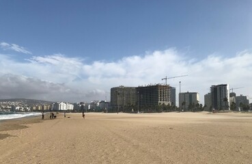 View of a large sandy beach in a windy cloudy day with cane and building in construction in horizon