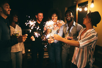 Happy friends celebrating with fireworks at new year's eve party - Soft focus on african man face