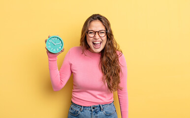 hispanic pretty woman shouting aggressively, looking very angry. alarm clock concept