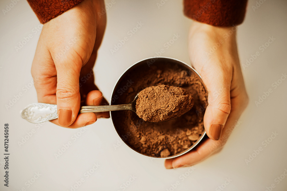 Wall mural a woman in a brown jacket and with a beige manicure takes out a portion of fragrant crumbly cocoa po