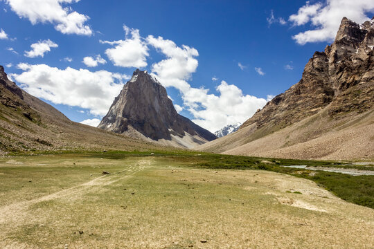 A grassy meadow in the village of Kargyak with the granite mountain peak of Mount Gumbok Rangjon on the Darcha Padum trekking route in the Zanskar valley in Ladakh..