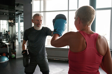 Woman exercising with trainer at boxing and self defense lesson