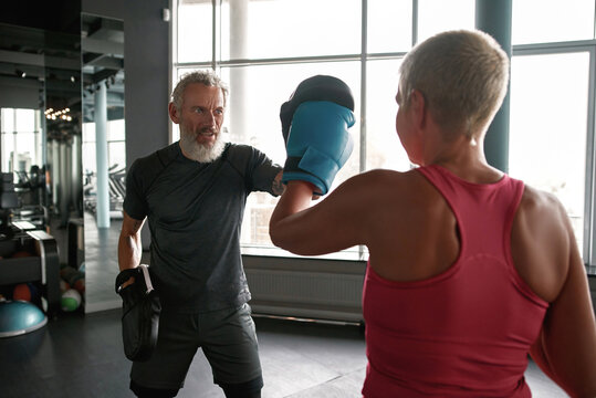 Woman exercising with trainer at boxing and self defense lesson