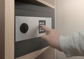 Close up of a man dials a combination of numbers on the digital lock of the safe
