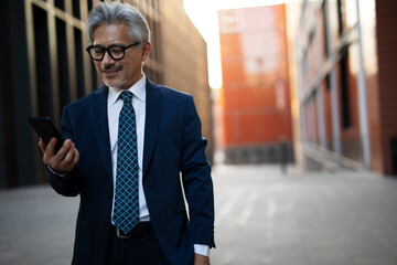 Senior businessman outdoors. Middle-aged businessman using the phone..