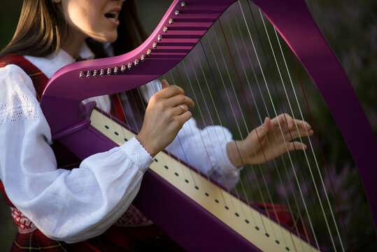 Beautiful Young Woman Playing Celtic Harp And Singing Song In Woodland