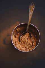 Top view of a jar with fragrant crumbly natural cocoa powder, in which lies a beautiful silver...