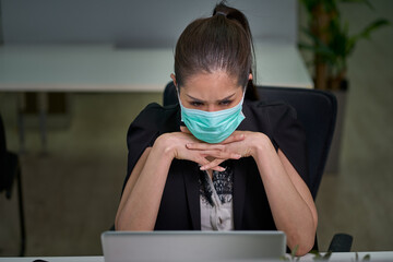 Businesswoman have a serious face and facial mask while teleconference by laptop in business office