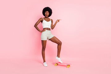 Fototapeta na wymiar Photo of crazy lady skateboarding direct finger empty space wear cropped top shorts shoes isolated pink color background