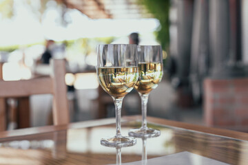 Two glasses of white wine on a wooden table on a vineyard