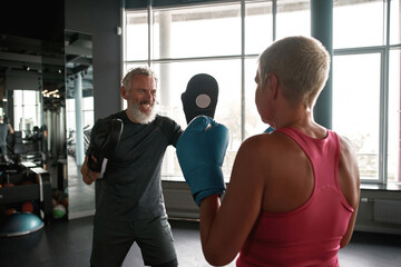 Fototapeta na wymiar Engaging boxing trainer teaches woman to self-defense