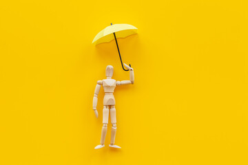 Insurance protection concept with wooden mannequin figure and umbrella