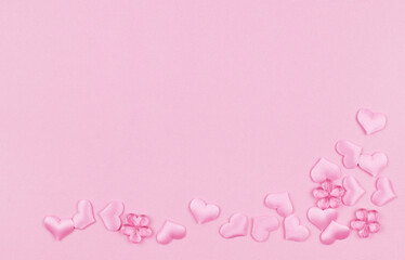 Pink satin hearts in a corner arrangement on paper texture for Valentine Day