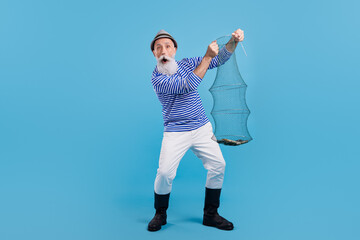 Full length photo of old happy positive man fisherman hold net catch good mood isolated on blue...