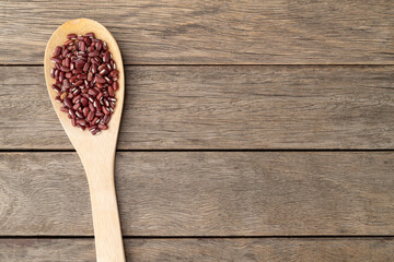 Azuki beans in a spoon over wooden table with copy space