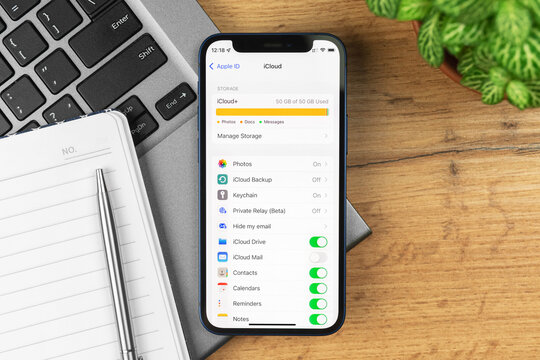 Kharkov, Ukraine - November 21, 2021: iCloud out of space screen on Apple iPhone, full storage settings. Business workspace, wooden table, top view photo