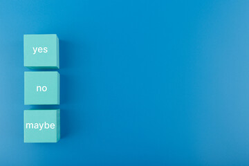 Yes, no and maybe written on blue toy cubes on blue background with copy space. Concept of positive...