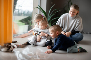 mother with her three children playing with a cat on the floor at home