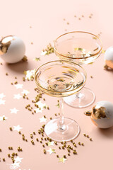 New Year champagne and Christmas gold baubles on pink background. Vertical format. Close up.