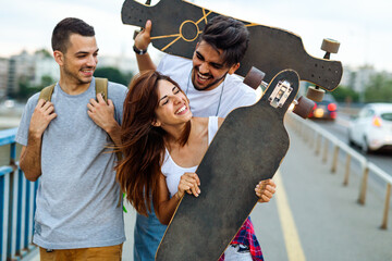 Group of happy teen people hang out together and enjoying skateboard outdoors.