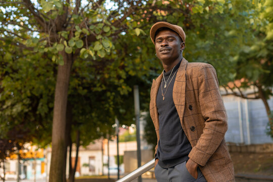 Hombre africano en traje, paseando por el parque con las manos en el bolsillo.