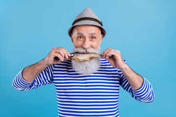 Portrait of attractive hungry cheerful grey-haired man biting fresh fish food carp isolated over...