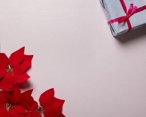 top view of poinsettia flowers and gift box on a white wooden table