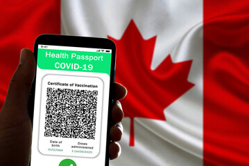 A covid vaccine certificate, also called covid passport, is seen on the screen of a mobile phone with the canadian flag in the background. The use of the covid passport is being discussed in Canada