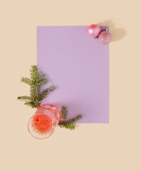 Minimal New Year concept with Christmas decoration and glass of drink on pastel purple and yellow background. Creative copy space holiday idea.
