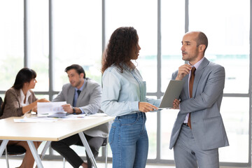 businesswoman and businessman using laptop computer and talking about work or project in office