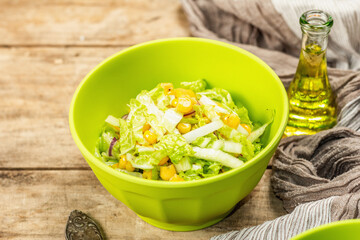 Tasty vegan salad from Chinese cabbage, sweet corn, purple onion, and dressing