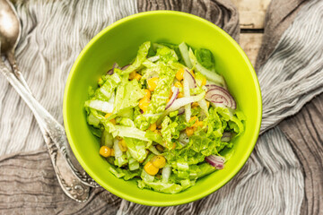 Tasty vegan salad from Chinese cabbage, sweet corn, purple onion, and dressing