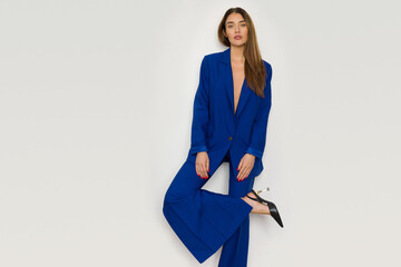 Fashion model in elegant navy blue suit is posing on one leg. - 471259648