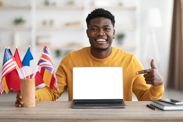Happy black guy showing language school on laptop, mockup © Prostock-studio