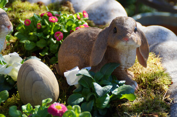 a cute easter bunny sitting in the flower bed on a sunny april day 