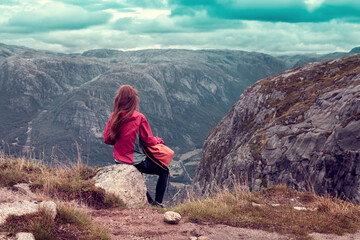 girl sitting on a stone and looking away the Norwegian mountains