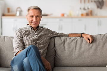 Contented Senior Man Sitting On Sofa Relaxing At Home