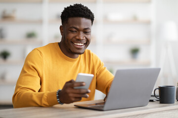 Young black man entrepreneur working on laptop and using cellphone