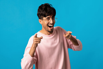 Handsome indian guy indicating at camera, posing on blue