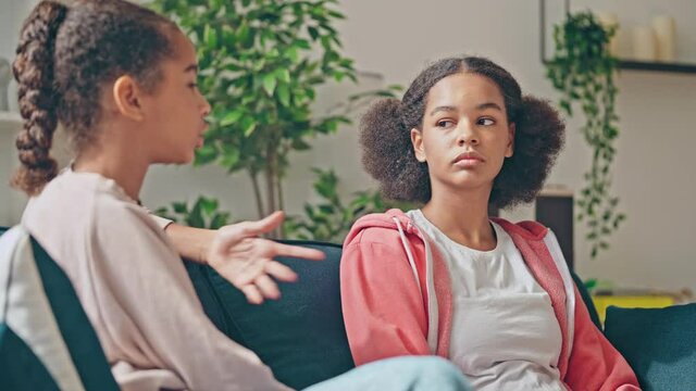 Sad teenage girls talking on couch, friends discussing problem to solve conflict