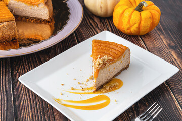 Delicious pumpkin cheesecake in white plate on wooden table