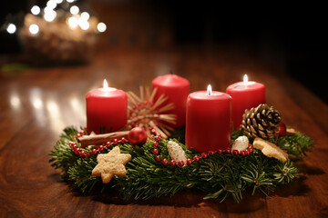 Third Advent - decorated Advent wreath from fir branches with red burning candles on a wooden table...