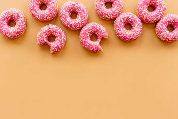 Fototapeta na wymiar Pattern of pink glazed donutes with sprinkles, top view