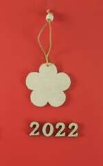 Wooden snowflake toy and wooden numbers 2022 on a red background. Eco-friendly new year 2022.