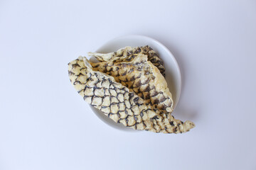 Fried fish skin or skin fish crackers, with visible pattern of fish scales. Isolated on white background