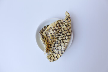 Fried fish skin or skin fish crackers, with visible pattern of fish scales. Isolated on white background